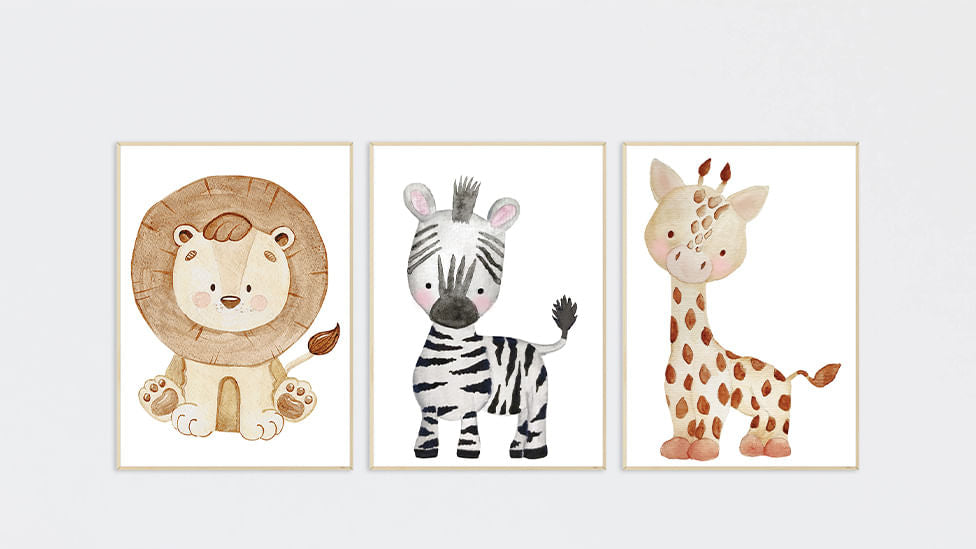 Conjunto de três quadros infantis de safári, com leão, zebra e girafa, alinhados na mesma altura em parede clara de quarto de bebê