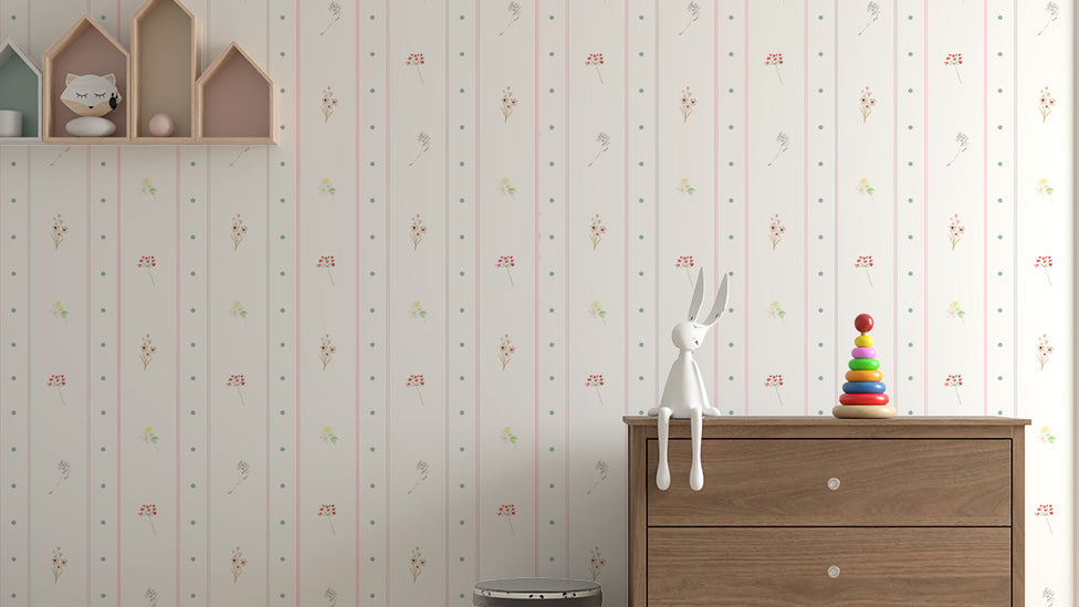 Quarto de bebê com papel de parede de listras e poá com flores, cômoda de madeira com brinquedos e prateleiras em forma de casinha