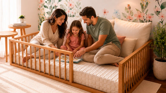 Mãe, pai e filha leem um livro sentados numa cama montessoriana baixa com grade de madeira