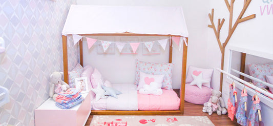 Quarto montessoriano de menina com cama baixa e prateleiras na altura da criança
